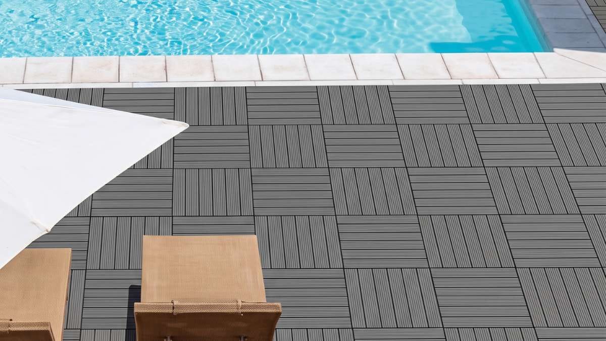 Barefoot person walking safely on a splinter-free grey WPC composite deck tile surround next to an outdoor swimming pool