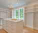 White modern walk-in closet with central drawer island and open hanging racks