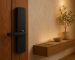 Modern smart door lock with a digital keypad and integrated camera installed at the proper height above a standard entry door handle.