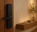 Modern smart door lock with a digital keypad and integrated camera installed at the proper height above a standard entry door handle.
